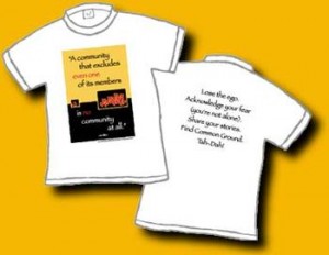 This is a 100% cotton white shirt. On the front is a large box – the top 2/3 school bus yellow, and the bottom black. There a red hearts scattered and words saying: “A community that excludes even one of its members is no community at all.” On the back in black letters it says: Lose the ego. Acknowledge your fear (you’re not alone). Share your Stories. Find Common Ground. Tah – Dah!  This is an original Dan Wilkin's design.